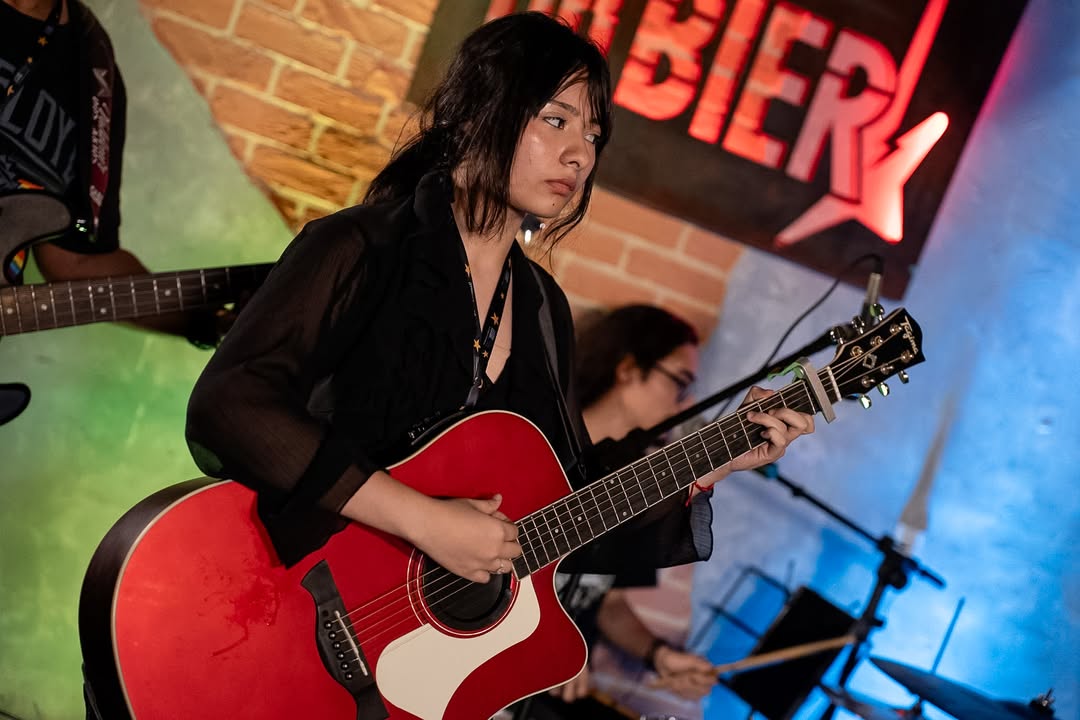 Aluno tocando violão em apresentação da Ponto Musical